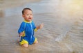 Portrait of Asian baby boy in swimming suit sitting on the sand beach