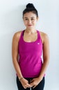 Portrait of Asian beautiful energetic healthy sportive woman with hair tied wearing pink or purple tank top, standing on white