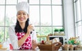 Portrait Asian beautiful female chef cooking breakfast in kitchen at home, holding glass and drinking milk, smiling with happiness Royalty Free Stock Photo