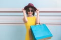 Portrait of asian beautiful girl wearing yellow dress and sunglasses holding shopping bags Royalty Free Stock Photo