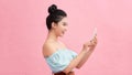 Portrait Asian beautiful happy young woman standing smile, holding mobile phone her looking back to space on pink background Royalty Free Stock Photo