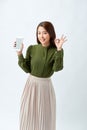 Portrait Asian beautiful happy young woman standing smile, holding mobile phone and showing ok gesture Royalty Free Stock Photo