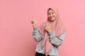 Portrait of Asian beautiful young muslim woman pointing both hands with finger on upper side with smile face Royalty Free Stock Photo