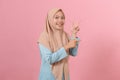 Portrait of Asian beautiful young muslim woman pointing both hands with finger on upper side with smile face Royalty Free Stock Photo