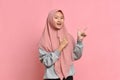 Portrait of Asian beautiful young muslim woman pointing both hands with finger on upper side with smile face Royalty Free Stock Photo