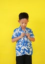 Portrait of Asian boy child buttoning up their own shirt isolated on yellow studio background Royalty Free Stock Photo