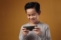 Portrait of Asian boy plays online game on his phone, smiling happy face, kid with gadget Royalty Free Stock Photo