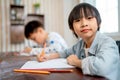 Portrait of Asian boy sit with look at camera while his friend concentrate to drawing or painting the picture in the back of Royalty Free Stock Photo