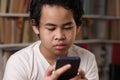 Portrait of Asian boy using his smart phone, student in library Royalty Free Stock Photo