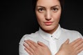 Portrait of Asian brunette woman in white shirt with arms crossed on chest on black background Royalty Free Stock Photo