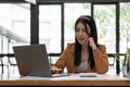 Portrait of asian business woman paying bills online with laptop in office. Beautiful girl with computer and chequebook Royalty Free Stock Photo