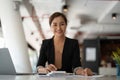 Portrait of asian business woman paying bills online with laptop in office. Beautiful girl with computer and chequebook Royalty Free Stock Photo