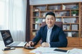 Portrait of Asian businessman working with papers and documents, man smiling and looking at camera, boss at work at desk in office Royalty Free Stock Photo
