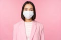 Portrait of asian businesswoman in medical face mask, wearing suit, concept of office work during covid-19 pandemic Royalty Free Stock Photo