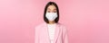 Portrait of asian businesswoman in medical face mask, wearing suit, concept of office work during covid-19 pandemic Royalty Free Stock Photo