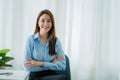 Portrait of an Asian businesswoman sitting at her desk with her arms crossed and smiling at the camera. white cloth background Royalty Free Stock Photo