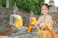 Portrait of asian child girl in traditional thai dress praying against old buddha statue at ayutthaya in thailand Royalty Free Stock Photo