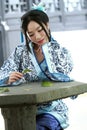 Portrait of Asian Chinese girl in traditional dress, wear blue and white porcelain style Hanfu, sit on a stone chair