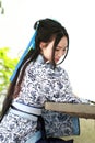 Portrait of Asian Chinese girl in traditional dress, wear blue and white porcelain style Hanfu, sit on a stone chair Royalty Free Stock Photo