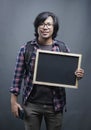Portrait of Asian College Student Holding Blackboard on Grey Background. Smile at Camera Royalty Free Stock Photo