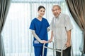Portrait of Asian disabled Senior Elderly male stand with walker enjoy stay home nursing care. Beautiful nurse caregiver woman bes