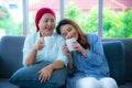 Asian elderly mother who recover from cancer and her daughter are sitting on a couch holding a cup of drink and talking to one