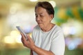 Portrait of asian elderly woman smiling with using mobile phone and colorful bokeh background Royalty Free Stock Photo