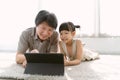 Portrait of Asian father and cute little daughter watching cartoons using digital tablet gadget e-books for kids on-line lying on Royalty Free Stock Photo