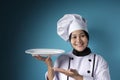 Asian Female Chef Shows Empty White Plate, Presenting Something, Copy Space Royalty Free Stock Photo