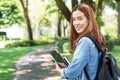 Portrait of asian female colleges student holding textbook in her hands and standing outdoors at university campus