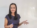 Asian female teacher  standing at white board in front of  classroom,  talking to the student, looking at camera. Education Royalty Free Stock Photo