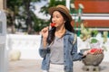 Portrait of Asian female traveler eating a slice of water melon while walking on sidewalk of buddhist temple on street Royalty Free Stock Photo