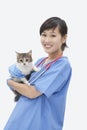 Portrait of Asian female veterinarian holding cat over gray background