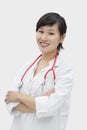 Portrait of an Asian female veterinarian standing arms crossed over gray background