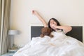 Portrait of asian girl awaking, wake up on the bed. cute asian girl stretching her arms Royalty Free Stock Photo