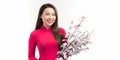 Portrait of Asian girl hands holding peach blossom, in traditional red ao dai standing on plain background