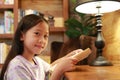 Portrait of Asian girl kid in casual clothes reading a book and smiling on the desk in the room Royalty Free Stock Photo