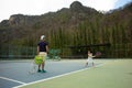 Portrait Asian girl plays tennis with her father and coach at outdoor court with stone mountain and forest background