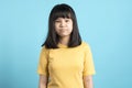 Portrait of Asian grumpy little girl on blue background.