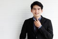 Portrait of an asian handsome business man wearing formal black suit, tie his necktie,  smiling with confidence and happiness and Royalty Free Stock Photo