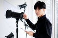 Portrait of an asian handsome male photographer or cameraman wearing casual black shirt, posing and looking into camera while Royalty Free Stock Photo