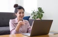 Portrait Asian of happy beautiful young woman work from home she sitting on sofa raise hand and say hello on laptop computer in Royalty Free Stock Photo