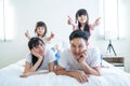 Portrait of Asian happy family smile and look at camera on bed at home. Loving couple and young little girl sibling daughters Royalty Free Stock Photo