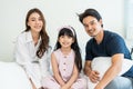 Portrait of Asian happy family smile and look at camera on bed at home. Loving couple and young little girl sibling daughters Royalty Free Stock Photo