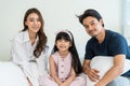 Portrait of Asian happy family smile and look at camera on bed at home. Loving couple and young little girl sibling daughters Royalty Free Stock Photo