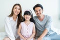 Portrait of Asian happy family smile and look at camera on bed at home. Loving couple and young little girl sibling daughters Royalty Free Stock Photo