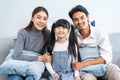 Portrait of Asian happy family smile, look at camera on sofa at home. Loving man and woman couple with young little cute girl Royalty Free Stock Photo