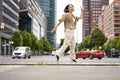 Portrait of asian happy girl jumping and dancing in city centre, posing on streets, express joy and excitement Royalty Free Stock Photo