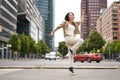 Portrait of asian happy girl jumping and dancing in city centre, posing on streets, express joy and excitement Royalty Free Stock Photo