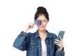 Portrait Asian happy young girl in jeans shirt smiling cheerful and showing plastic credit card while holding mobile phone Royalty Free Stock Photo
